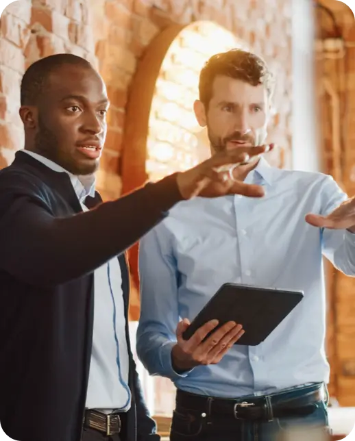 Two professionals discussing a project while one holds a tablet.