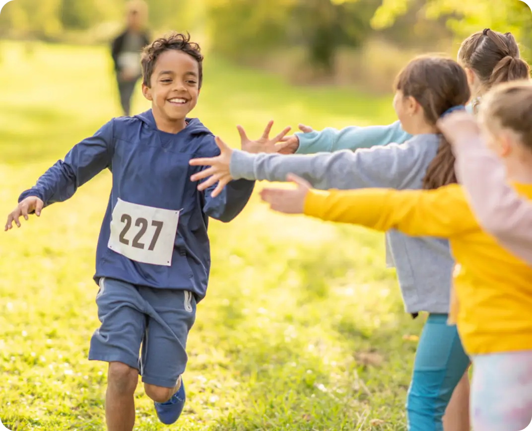 Children cheering on a boy during an outdoor race.