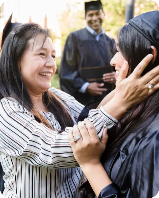 Woman celebrating with a graduate at an outdoor ceremony.