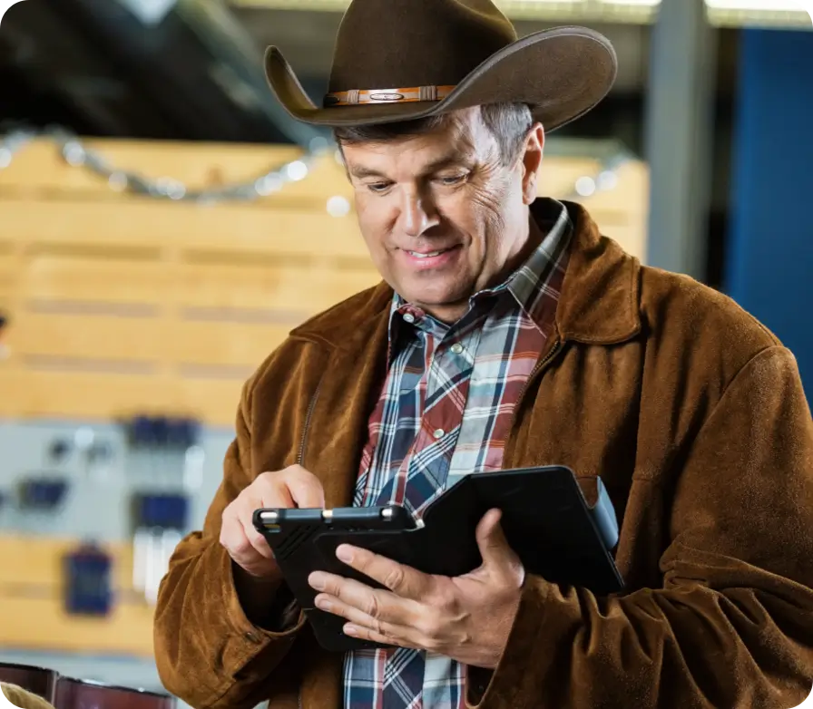 Man in a cowboy hat using a tablet indoors.
